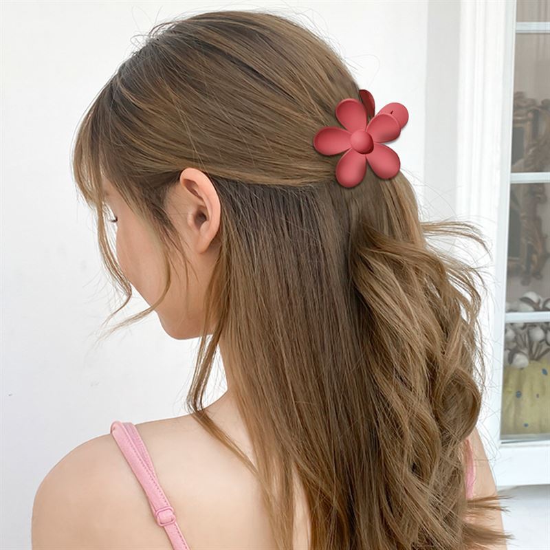A woman with long, wavy brown hair wears the SOHO Bloom Hair Claw in Yellow by SOHO, styled indoors with her back mostly to the camera.
