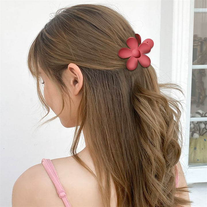 A woman with long, wavy brown hair wears the SOHO Bloom Hair Claw in Yellow by SOHO, styled indoors with her back mostly to the camera.
