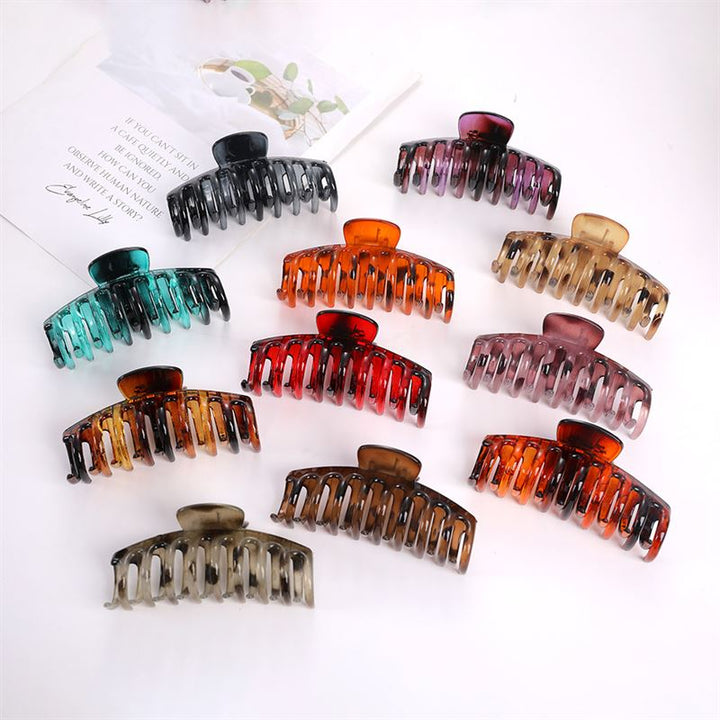 Ten SOHO Kana Hair Claw - Tortoise clips from SOHO, designed for all hair types and offering a strong grip, are displayed in rows on a white surface. These colorful claws include black, teal, red, pink, brown, amber, orange, and tortoiseshell styles.