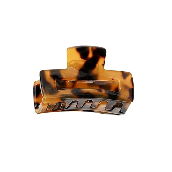 The SOHO Leia Mini Hair Claw - Tortoise by SOHO features a brown tortoiseshell pattern, curved design, and interlocking teeth for secure hold—perfect as a small hair clip for easy styling and keeping hair in place.