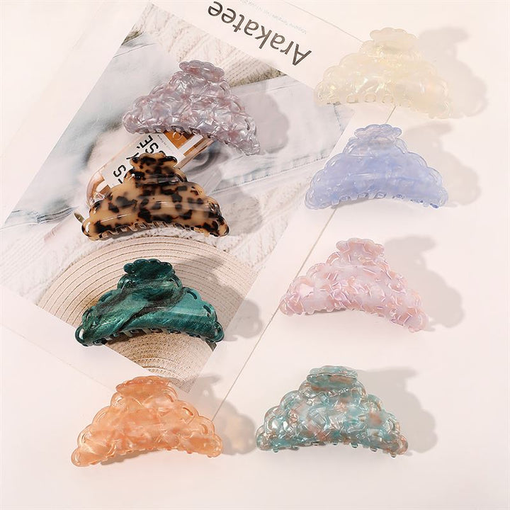 Seven SOHO Naomi Hair Claw - Sunshine clips from SOHO, featuring various patterns and pastel shades, are displayed on a white surface and magazine—perfect vibrant accessories for elevating any hairstyle.