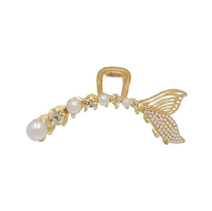 The SOHO Umi Hair Claw by SOHO features a gold fish-shaped design with pearls, rhinestones, and a textured tail fin for an enchanting mermaid-inspired look.