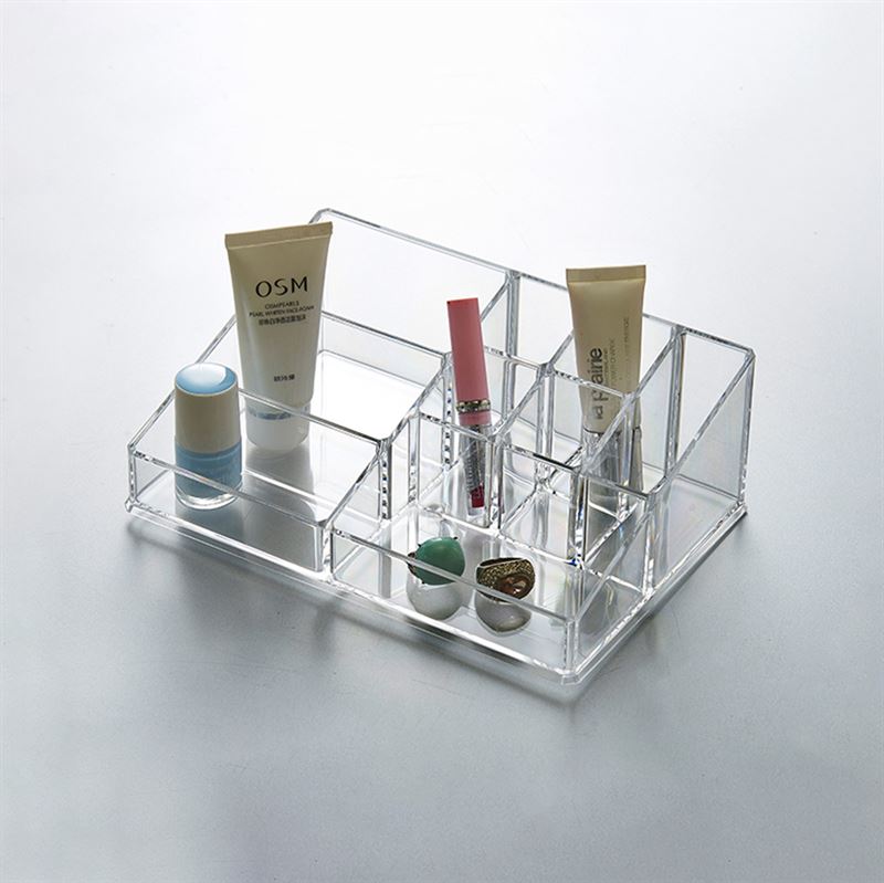 The UNIQ Make Up Acrylic Organiser - SF-1611D (U304) by UNIQ neatly arranges tubes of cream, a stick, lipstick, lip balm, and round containers in clear compartments on a light surface.